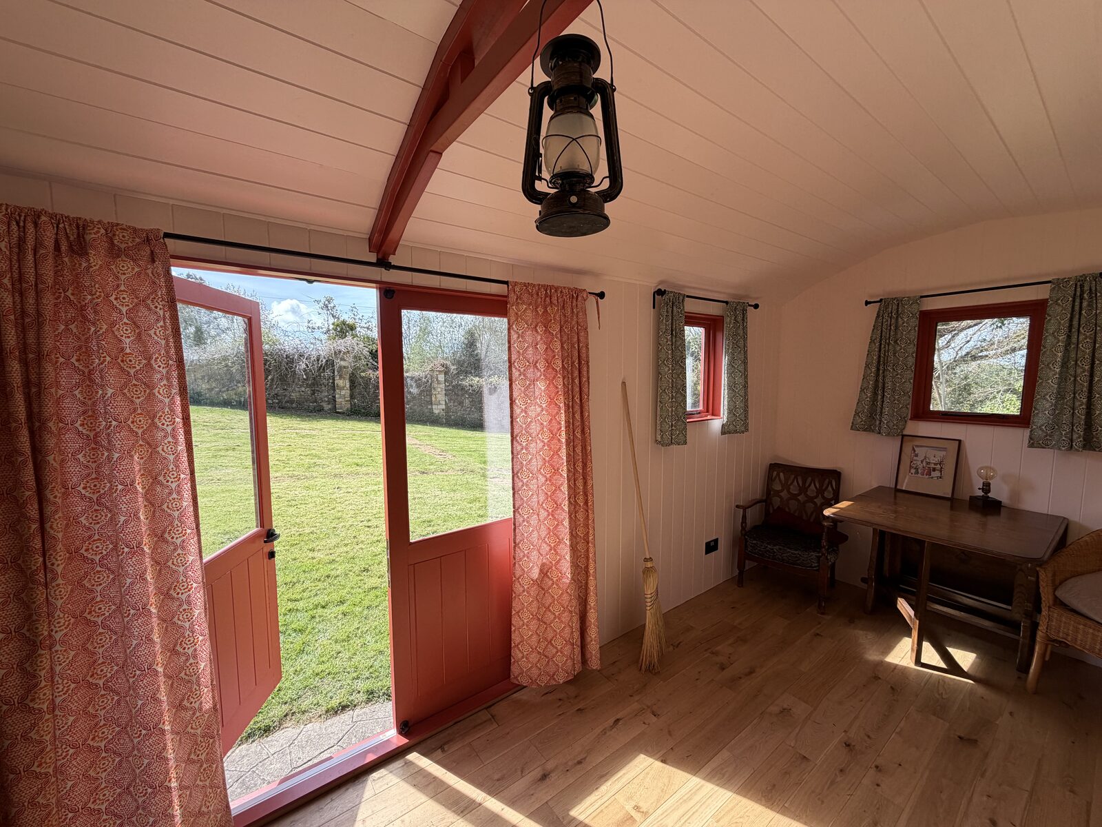 Inside the shepherd's hut — bright living and dining space with doors onto the garden