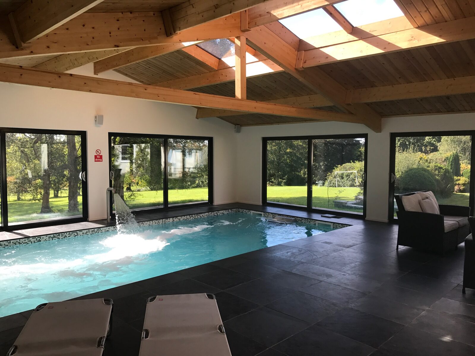 Heated indoor swimming pool with garden views through floor-to-ceiling glass