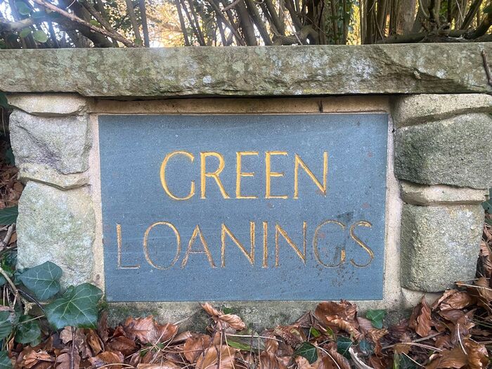 The carved Green Loanings sign at the entrance