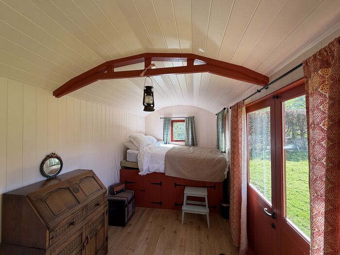 Inside the shepherd's hut — bed beneath a vaulted timber ceiling